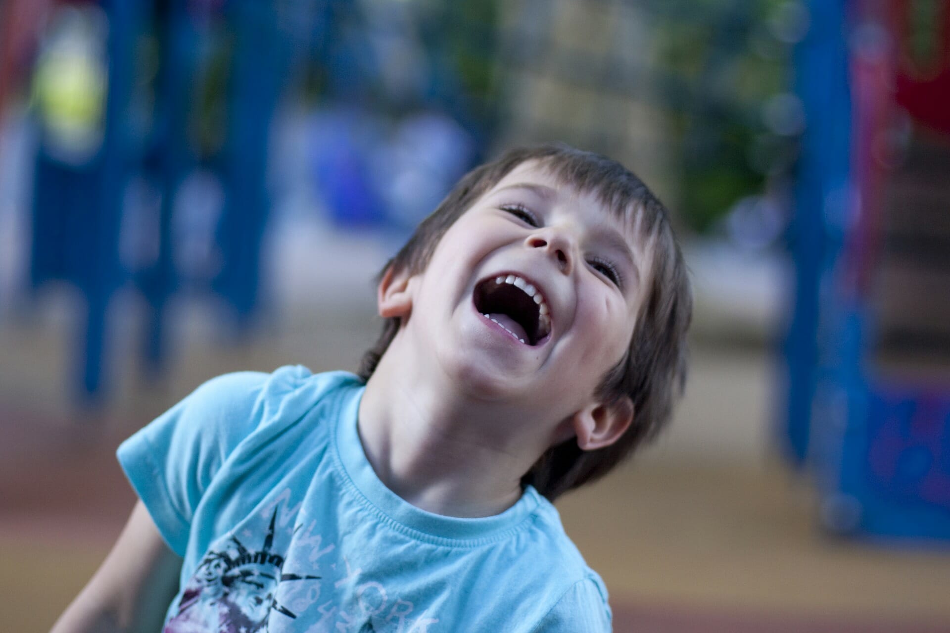 a young boy throwing his head back with laughter