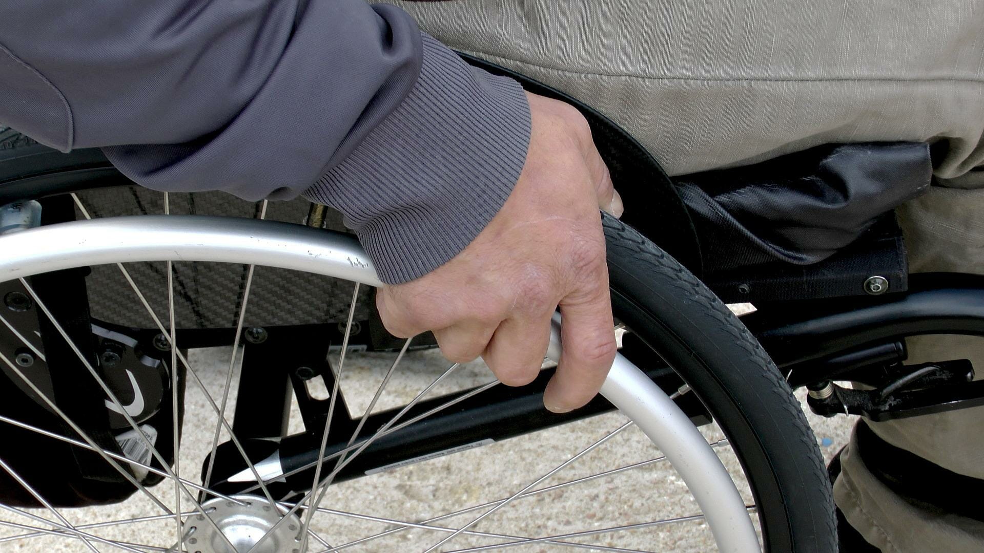 close up image of a wheelchair wheel and a mans hand