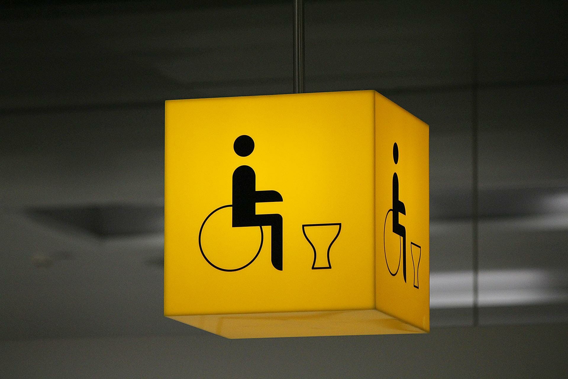 an illuminated sign shows the way to a disabled toilet