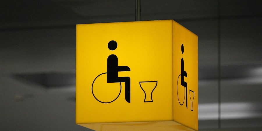 an illuminated sign shows the way to a disabled toilet